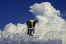 workman in high vis jacket bent over, super-imposed on cloud background