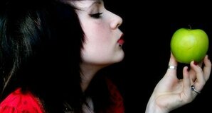 Punk-styled girl with piercing gazes at an apple 