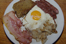 A hearty breakfast of scrapple, fried egg on toast, bacon, sausage and fried mushrooms