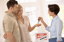 An estate agent hands keys to a couple after house sale. Photo by Shutterstock