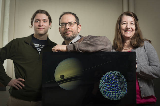Grad James Stevenson, astronomer Jonathan Lunine and chemical engineer Paulette Clancy, with a Cassini image of Titan in the foreground of Saturn, and an azotosome, the theorised cell membrane on Titan. Credit: Cornell University