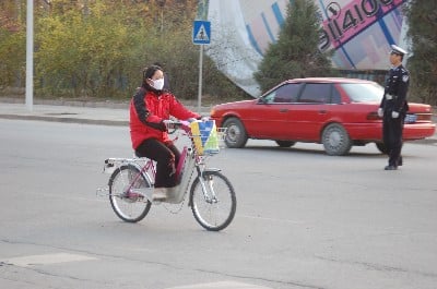 Shot of a girl with a mask biking through Beijing