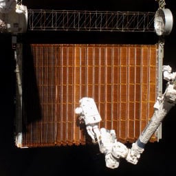 A spacewalker works on a section of solar panelling