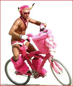 Shot of pink haired Styn shirtless on a pink bike 