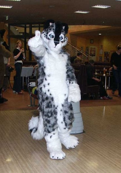 black and white feline furry on dance floor, giving thumbs up to camera