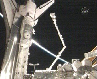 An astronaut on the end of a robotic arm. Credit: NASA TV