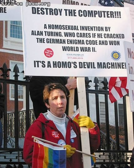 Gay right protester holding banner decrying the homo devil machine