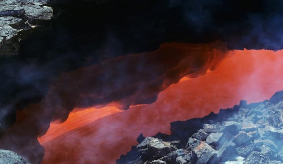 View down a skylight revealing magma racing through a lava tube in Hawaii. Credit: Mark Robinson