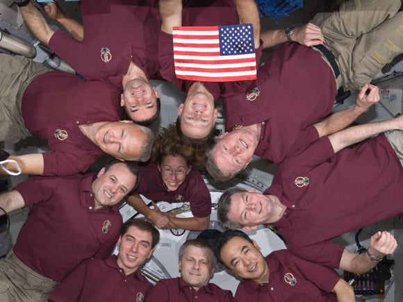 The Atlantis and ISS crew members pose with US flag. Pic: NASA