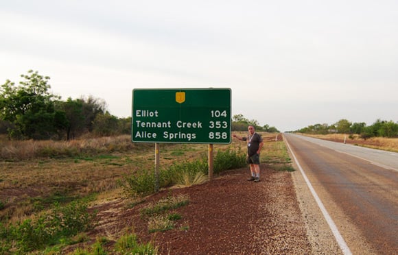 Lester by a Stuart Highway sign showing the distance to Alice Springs