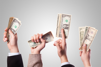 hands waving dollar bills in the air