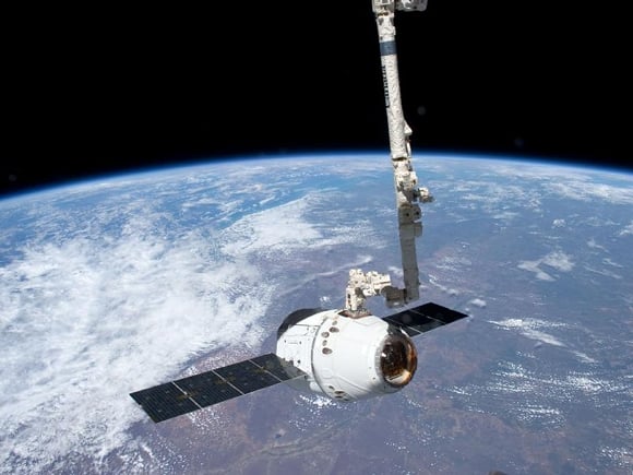 SpaceX Dragon on the Canadarm over Earth