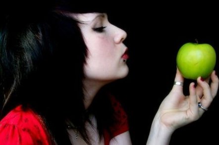Punk-styled girl with piercing gazes at an apple