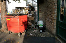 big red wheelie bin and pallet full of rubbish in London street
