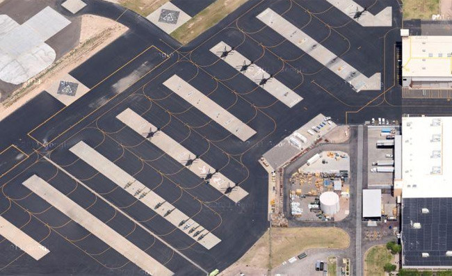 A wide aerial view of an airfield with black helicopters