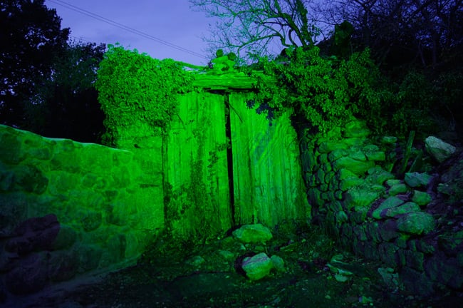 A ruined stone building illuminated by laser
