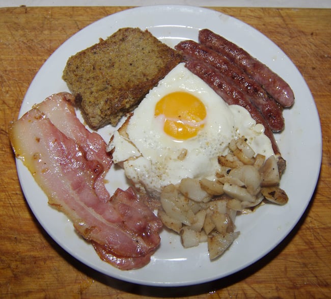 A hearty breakfast of scrapple, fried egg on toast, bacon, sausage and fried mushrooms