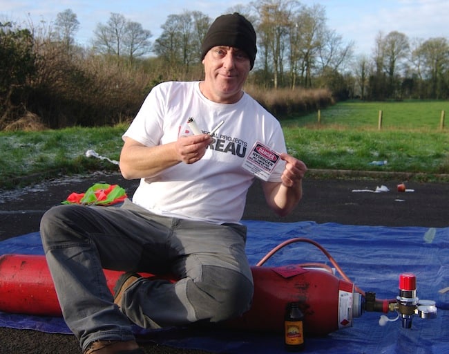 Lester poses with cigarette and lighter while sitting on the hydrogen cylinder