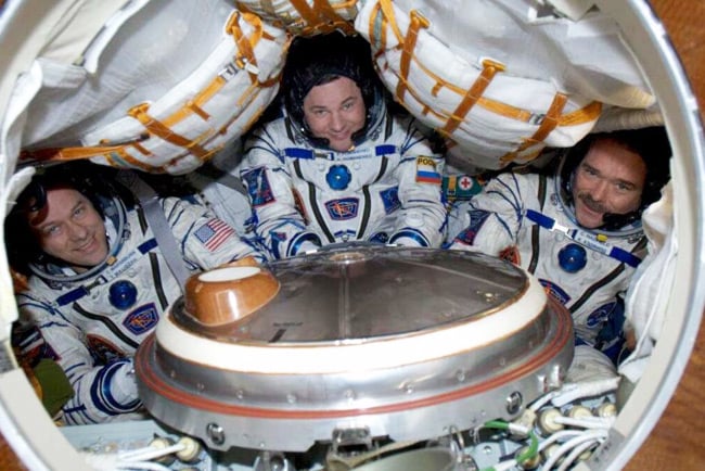 Tom Marshburn (L), Roman Romanenko (C) and Chris Hadfield (R) squeeze into a Russian Soyuz-TMA capsule shortly before their return to Earth.