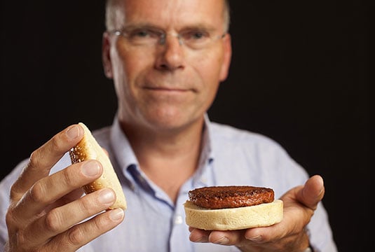 Photo of Dr. Mark Post holding a burger made from cultured beef