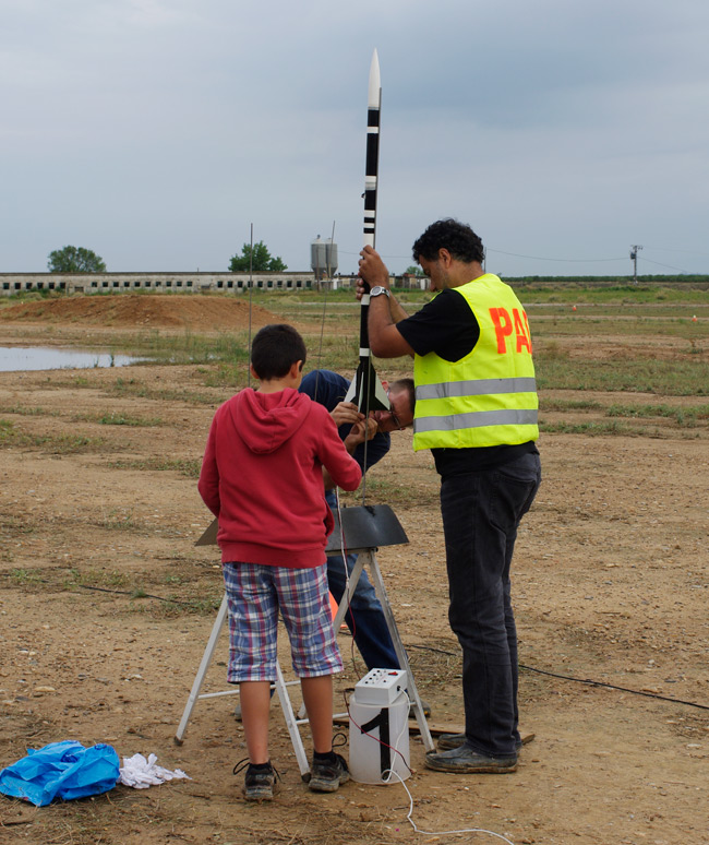 Three rocketeers mount their rocket on the launch rail