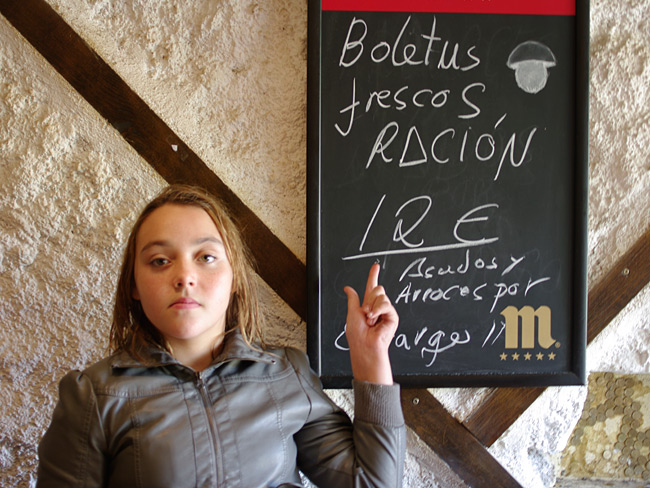 Kati in a local bar indicating the price of 12 euros for a small plate of Boletus