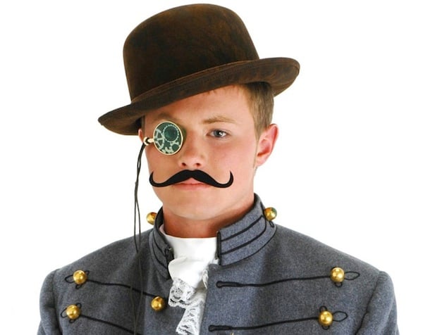 Boy in steampunk fancy dress, with hat, mechanical monocle, waxed moustache, cravat and Bavarian-type jacket