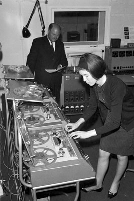 Delia Derbyshire edits on a Philips EL3503 while Desmond Briscoe checks the script