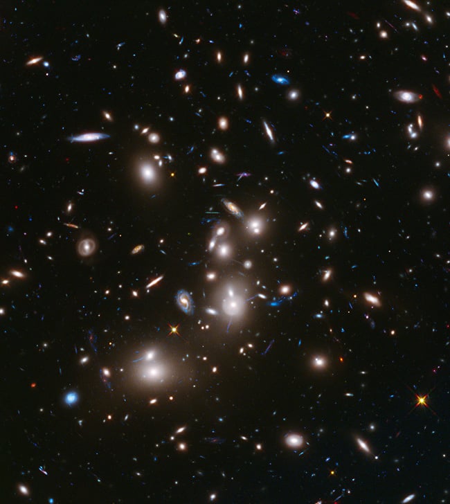 Long-exposure Hubble Space Telescope image of massive galaxy cluster Abell 2744 (foreground) and some of the faintest and youngest galaxies ever detected in space.