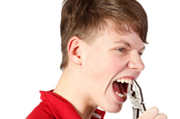 Youth gripping his front teeth with a pair of pliers