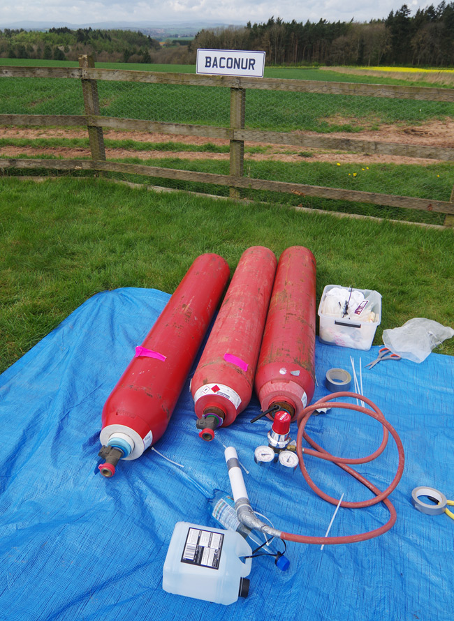 Bottles of hydrogen with a 'Baconur' sign in the background