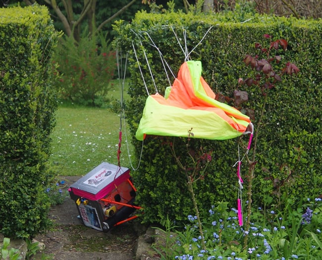 The payload and parachute in a garden hedge