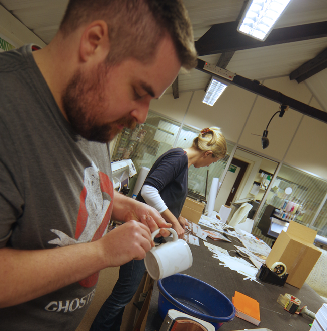 Chris peeling the paper off the mug after extraction from the machine