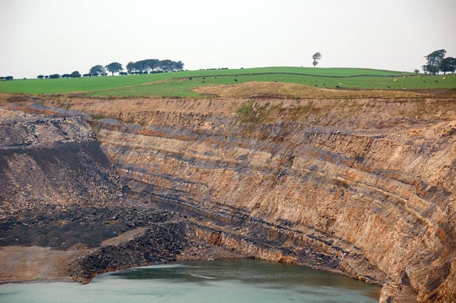 The northern end of the huge water-filled pit, showing the coal seams in the rock at Broken Cross Muir opencast coal mine