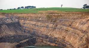 The northern end of the huge water-filled pit, showing the coal seams in the rock at Broken Cross Muir opencast coal mine