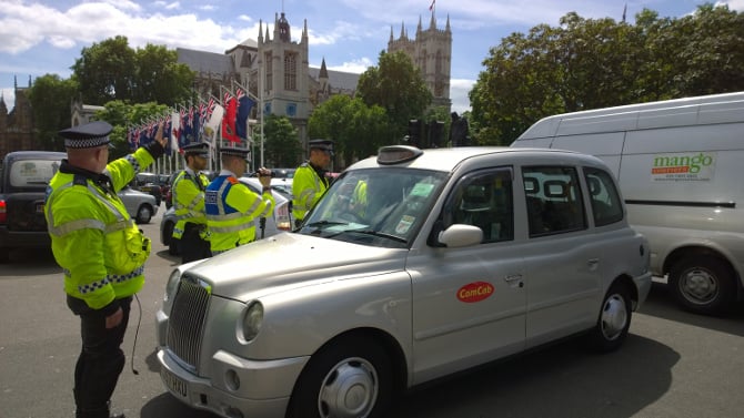 Police direct a cabbie at the Uber protest in London