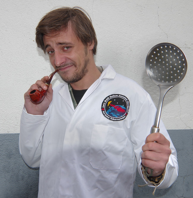 Matthew Haines poses with lab coat, pipe and kitchen implement