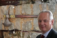 Cabinet Office minister Francis Maude against bakdrop of '70s stone facade with old axes hung up on wall (background by Michael Coghlan, licensed under CC 2.0