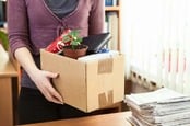 Woman packs up contents of desk. Image via shutterstock