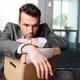 Sad man stares glumly over boxed contents of desk. Image via shutterstock (Baranq)
