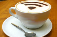a coffee cup topped with cappucino foam with a wi-fi symbol sprinkled on top in powdered chocolate