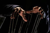 A puppeteer holding up some strings