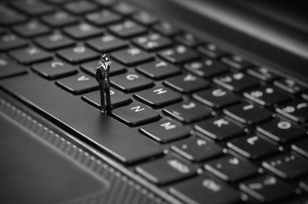 Tiny toy policeman inspects keyboard. Image via Shutterstock