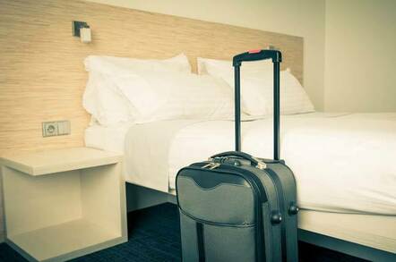 Hotel scene - suitcase propped up against freshly made bed. Image by Shutterstock