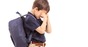 Boy with a backpack hides his eyes and cries. Pic by Shutterstock
