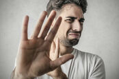 Disgusted man holds his hand up to obscure his view. Pic via Shutterstock