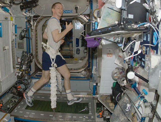Frank De Winne on a treadmill in zero gravity (leg chained to bottom of craft). Pic via NASA