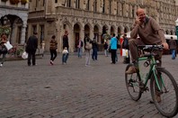 Man on bicycle talks on mobile on busy Brussels street. Photo by Alredo Cerra via Shutterstock