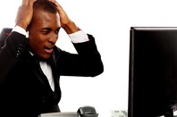 Irritated man looks at office desktop screen in frustration. Photo by Shutterstock