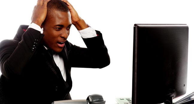 Irritated man looks at office desktop screen in frustration. Photo by Shutterstock